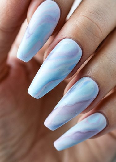 Elegant pastel marble nail art design on long, almond-shaped nails for a sophisticated look.