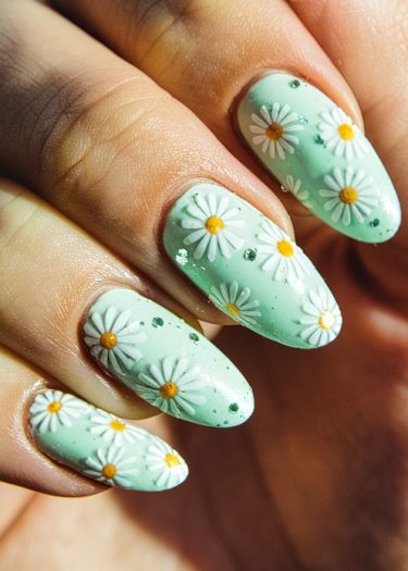 Pastel mint green nail art featuring daisies and speckles for a fresh spring look.