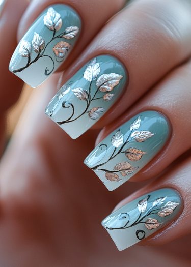 Elegant pastel mint nails adorned with metallic silver leaves for a sophisticated manicure.