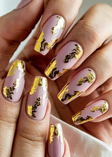 Elegant pastel pink nail art with gold foil accents and artistic dark elements for sophistication.