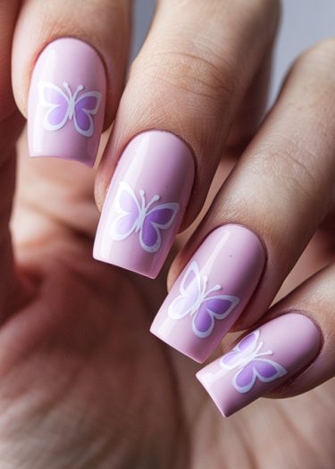 Elegant pastel pink nails with white butterfly art for a stylish, feminine look.