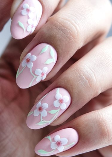 Elegant pastel pink floral nail art featuring white flowers and green leaves for a fresh look.