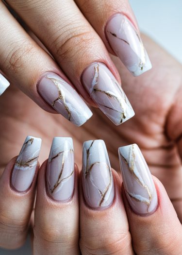 Sophisticated pastel pink marble nails with luxurious gold accents and artistic design details.