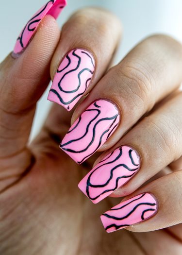 Vibrant pink nail art with intricate black patterns on elegantly manicured nails.