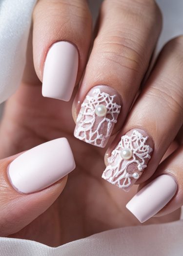 Elegant pastel pink nail art with 3D lace and pearl accents for a luxurious look.