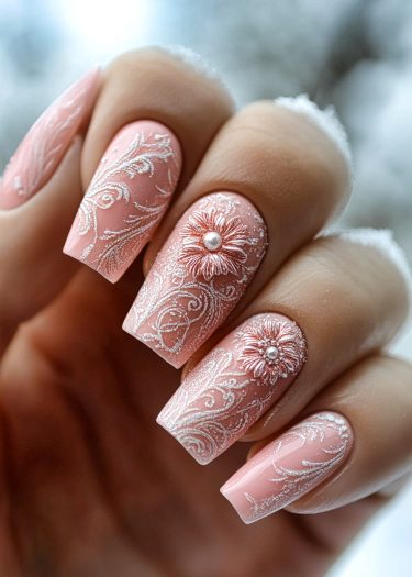 Elegant pastel pink nail art with lace design and floral embellishments featuring pearls.