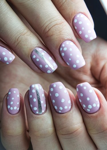 Pastel pink polka dot nails with elegant silver stripes for a chic nail art design.