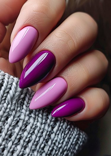 Elegant light pink and dark purple almond-shaped nails against a cozy gray sweater background.