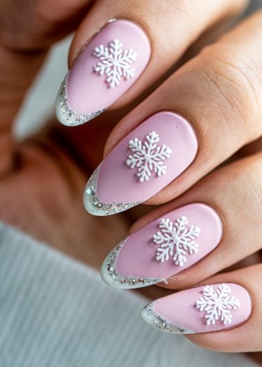 Elegant pastel pink nail art featuring 3D snowflakes and glitter tips for winter style.