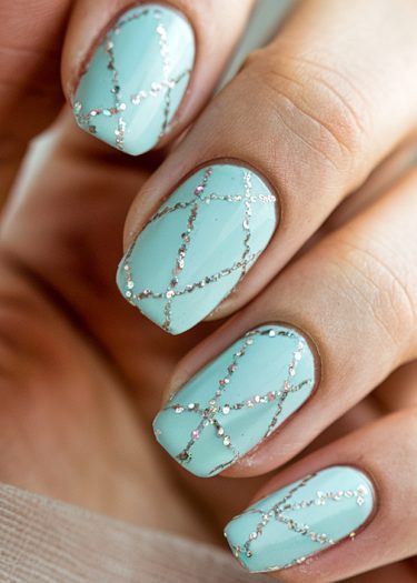 Elegant pastel turquoise nails with silver crisscross design showcase sophisticated nail art.