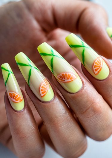 Vibrant lemon-yellow nails with orange slices and green vines for a cheerful summer look.