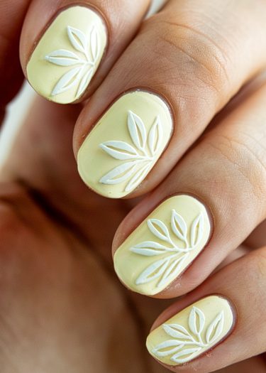 Elegant pastel yellow nail art with floral relief design, perfect for any occasion.