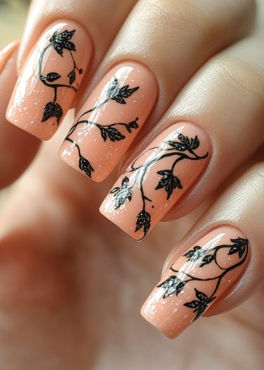 Elegant peach nail art with shimmering black vine designs for a chic, sophisticated look.