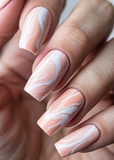 Sophisticated peach and white marbled nail art on elegantly manicured hands.