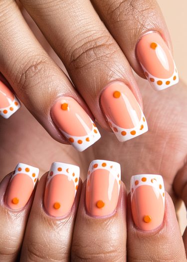 Elegant peach and white manicure with orange accents and textured dots for modern nail art.