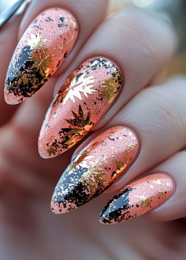 Elegant peachy pink almond nails featuring gold foil and black designs for sophisticated nail art.