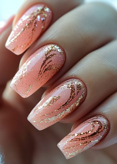 Elegant peach and pink almond nails with gold glitter art in a close-up view.