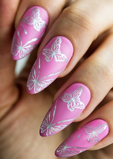 Vibrant pink almond-shaped nails featuring intricate white butterfly designs for stylish nail art.