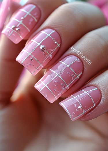 Elegant pink grid nail art with silver accents and glitter for a chic manicure.