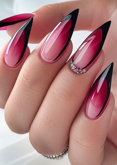 Elegant pink ombre stiletto nails with black outlines and sparkling rhinestones for a chic look.