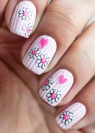 Vibrant pink-striped nail art featuring flowers and hearts for a playful manicure design.