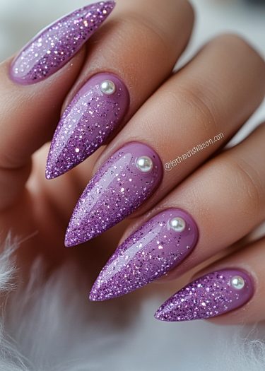 Lavender glitter nail art with pearl accents on elegant almond-shaped nails.