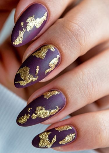 Elegant almond-shaped nails with matte purple polish and gold foil accents for a luxurious look.