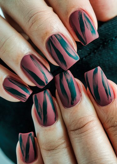 Elegant mauve matte nails with artistic black brush strokes for a chic statement.