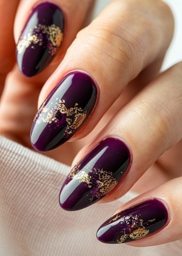 Elegant plum nails with artistic gold foil accents for a chic, sophisticated manicure look.