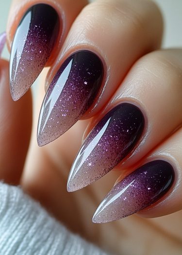 Impressive plum ombre glitter stiletto nails with a shimmering gradient and high-gloss finish.