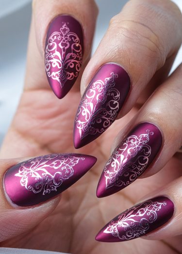 Stunning magenta stiletto nails with intricate white lace designs for elegant nail art inspiration.