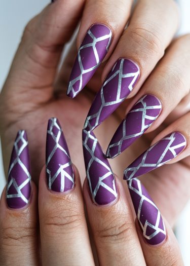 Stiletto purple nail art featuring metallic silver geometric designs for a chic, elegant look.