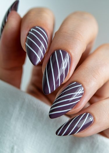 Elegant purple almond nails with intricate white designs for a sophisticated manicure look.