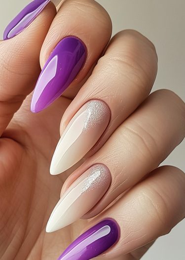 Stylish purple and white almond-shaped nail art with glossy finish and glitter accents.