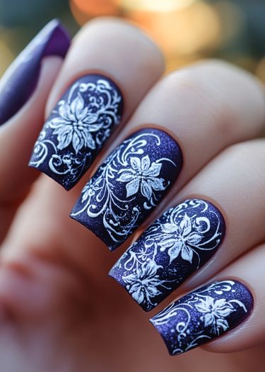 Elegant purple floral nail art featuring intricate white designs and shimmering details.