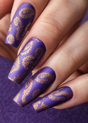 Impeccably manicured long purple nails with golden paisley nail art design.