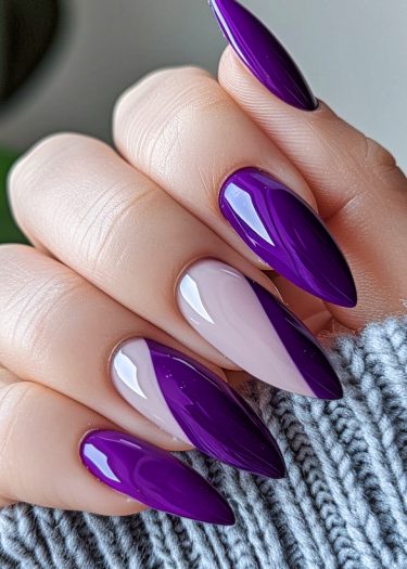 Elegant stiletto nails with purple and mauve designs showcased on a cozy gray fabric.