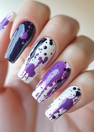 Stylish purple and black splatter nail art on coffin-shaped manicure for a creative look.