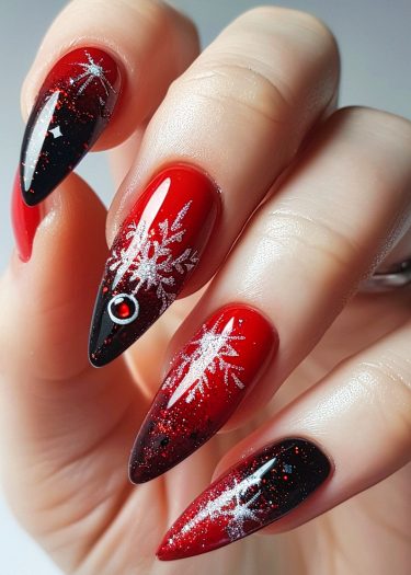 Elegant red-black gradient stiletto nails with winter snowflakes and a jeweled accent.