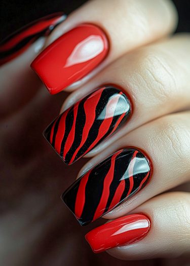 Bold red and black nail art with intricate designs and glossy finish.