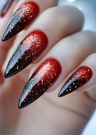 Stunning stiletto nails with black-to-red ombre and glitter for a bold, glamorous look.