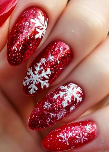 Elegant red glitter snowflake nail art in stiletto shape, perfect for festive occasions.