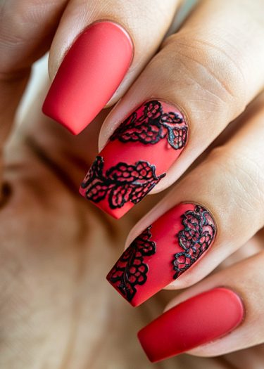 Elegant red matte nail art with intricate black lace accents for a sophisticated look.