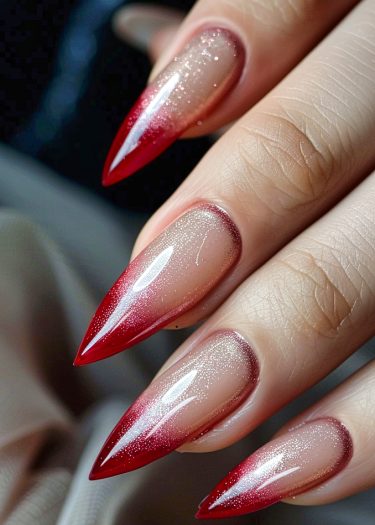 Stunning red ombre stiletto nails with glitter shine create a bold, glamorous manicure.