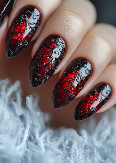 Elegant stiletto nails in rich red with intricate black lace design, showcasing luxury nail art.