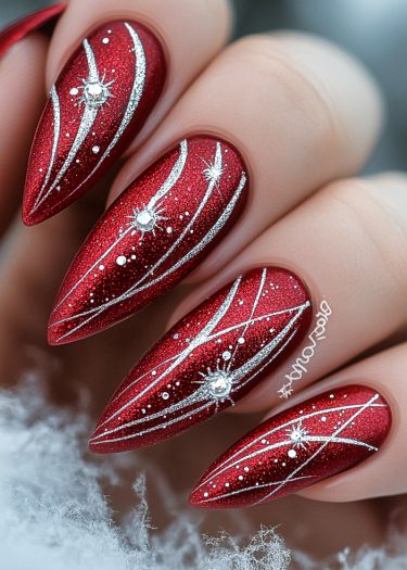 Glamorous red stiletto nails with intricate silver designs for a luxurious manicure look.