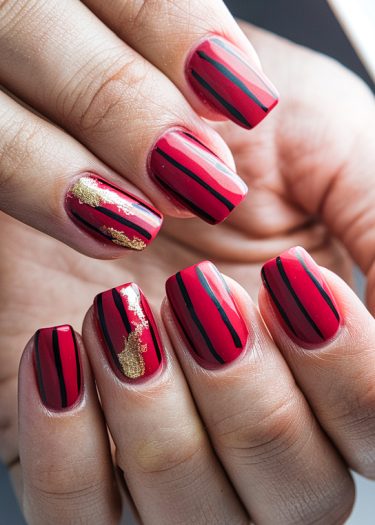 Stylish red striped nail art with gold accents for a bold, elegant look.