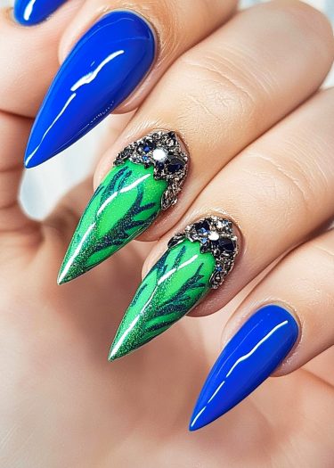 Stiletto nail art with royal blue and green designs, featuring intricate patterns and gems.