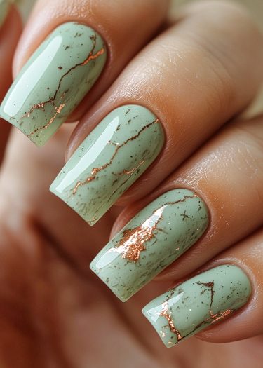 Elegant sage green nails with gold veins, showcasing a luxurious and modern nail design.