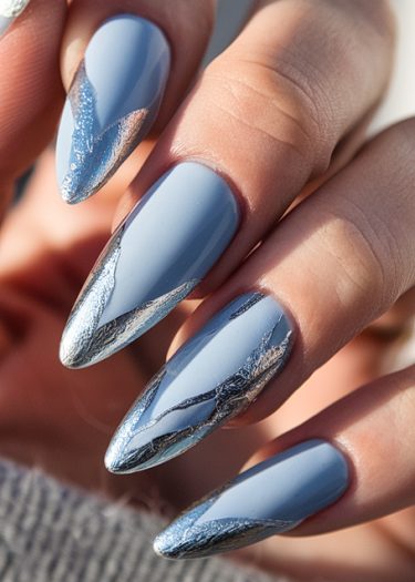 Sophisticated pastel blue almond nails with silver foil accents create elegant nail art design.